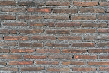 Close up of an old, weathered red brick wall. Rustic grunge texture with clay bricks and concrete mortar. Background.