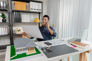 Confident young architect working at office desk, drawing house plans and discussing construction details on the phone, focusing on accuracy and creativity in architectural design and project planning