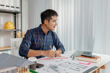 Confident young architect working at office desk, drawing house plans and discussing construction details on the phone, focusing on accuracy and creativity in architectural design and project planning