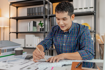 A young male architect is working with blueprints at his desk, using rulers and drawing tools to refine details. He appears focused and engaged, balancing creativity with precision.