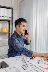 A young architect is multitasking at his desk, sketching blueprints, making phone calls, and reviewing notes. His workspace shows focus, productivity, and modern design work.