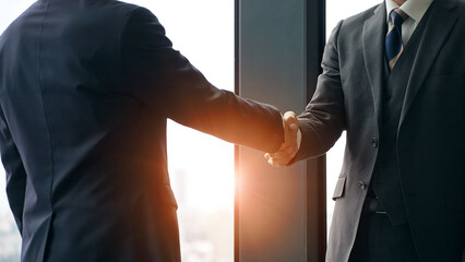 都市を背景に握手するビジネスパーソンのグループ