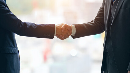 都市を背景に握手するビジネスパーソンのグループ