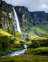 Obraz premium Majestic Waterfall Cascading Down Lush Green Mountain in Iceland.