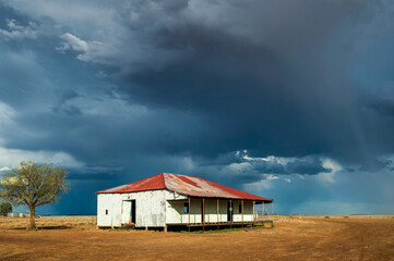 Old corrugated shed with a rusted roof beneath a brooding outback storm sky.