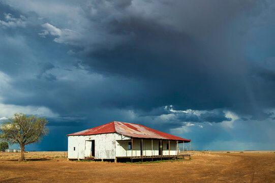 Old corrugated shed with a rusted roof beneath a brooding outback storm sky.