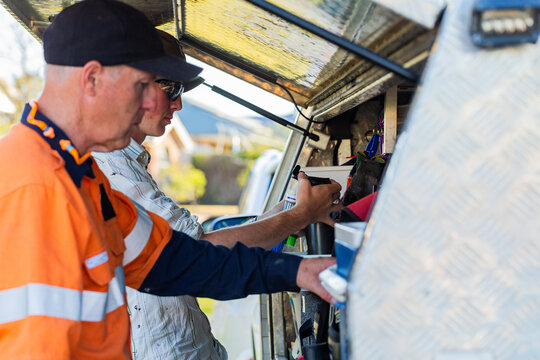 Father and son handyman business team working together by ute