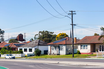 homes with tiled rooves on roadside with power pole line connecting houses to the electricity grid