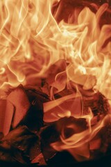 A close-up of the blazing orange and red flames of a bright, warm fire burning in a fireplace