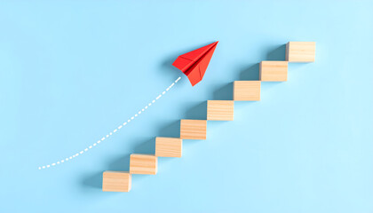 Creative concept of leadership and achievement with paper plane rising on step path against blue background.