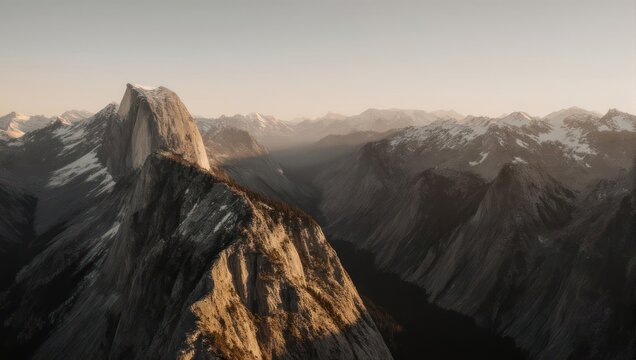 Panoramic mountain vista at golden hour.  Vast, rugged peaks stretch into a hazy sky