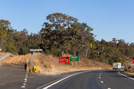 Arrester bed sign beside long steep descent on highway road in Australia