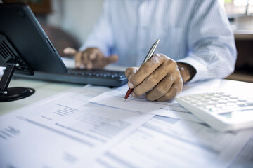 close-up shot, hand of asian man checking financial documents and business contract, working at home with tablet computer