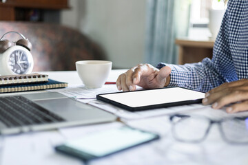 close up of hand, asian businessman using digital tablet working online with laptop and documents on desk at home