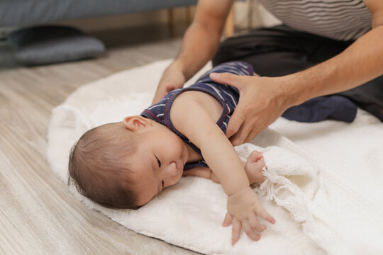 A father spends quality time with his baby, playing and bonding through gentle care and fun moments on a soft mat. The baby explores tummy time and pacifier use with support. - Powered by Adobe