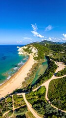Aerial view shows a sun-kissed beach, turquoise water, and lush greenery