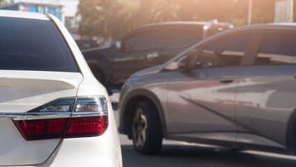 Rear side of white car driving on the road. Two cars cut off the right lane during rush hour in the...