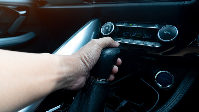 Close up of hand that controls the automatic gear lever. Grip to control the car to move forward for electric gear. Interiro of car with dark tone.