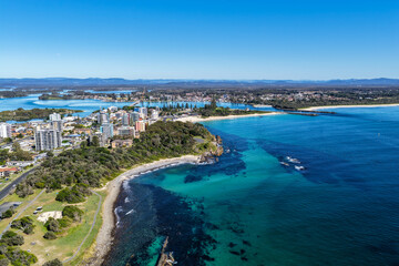 A breathtaking aerial view of Forster on the Mid North Coast of New South Wales, showcasing turquoise ocean waters, white sandy beaches, and the bridge linking Forster and Tuncurry. The scenic coastli