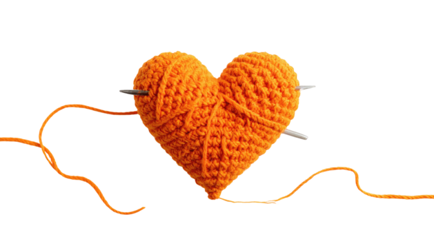 Knitted orange yarn heart impaled by needles against dark - Powered by Adobe