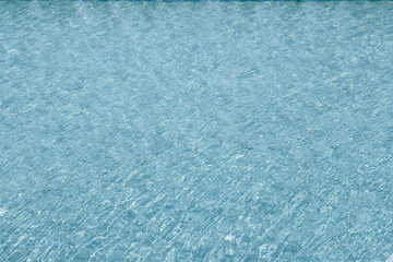 Vibrant blue water surface with shimmering reflections and ripples under sunlight