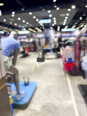 blurry image showing the interior of a shopping mall. The scene is out of focus, with indistinct shops, lights, and people walking.
