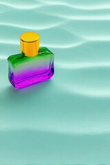 A rectangular perfume bottle with a gold cap and gradient glass from green to purple sits on a wavy teal surface.