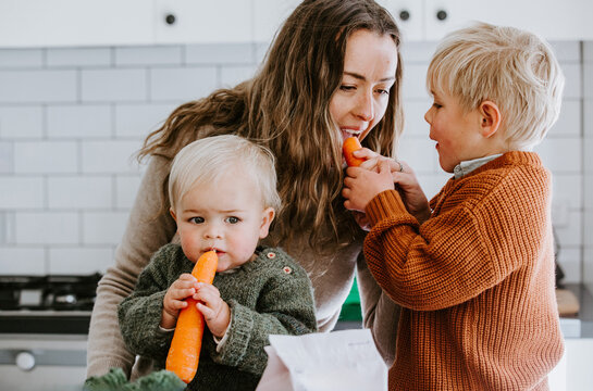 Young boys sharing fresh carrots with mum