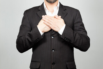 a businessman on suit doing a thankful expression with his hands over his chest and a white background