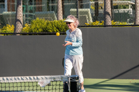 active senior woman playing pickleball outdoors