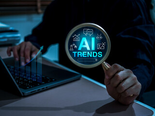 Magnifying glass showing "AI Trends" with icons and businessman using laptop, representing artificial intelligence insights, future technology trends, data analysis, and AI-driven innovation research.