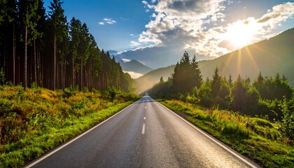 Asphalt road through a forest, mountains, and sunlit sky