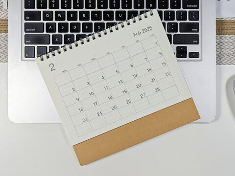 Minimalist desk setup with a 2026 February calendar placed on a laptop keyboard, concept of planning, scheduling, and time management for the new year.