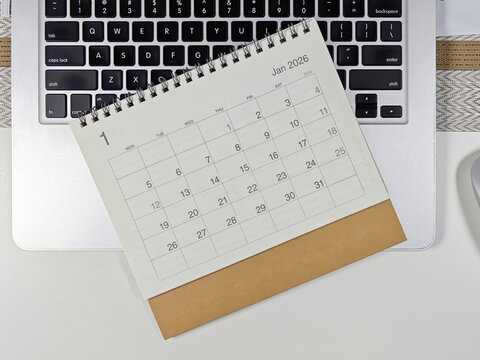 Minimalist desk setup with a 2026 January calendar placed on a laptop keyboard, concept of planning, scheduling, and time management for the new year.