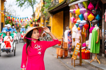 Young female tourist in Vietnamese traditional dress walking at Hoi An Ancient town in Vietnam