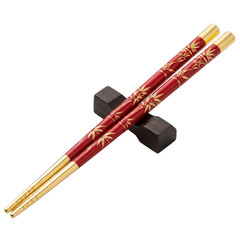 Elegant red and gold ornate chopsticks resting on a dark chopstick rest isolated on transparent background