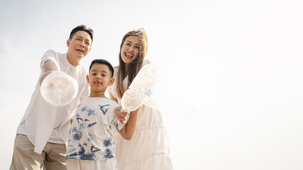 family, conservation, environmental, clean, beach, holiday, asian, fun, happy, happy family, outdoors, father, son, parents, Happy Asian family holding plastic bottles while cleaning the beach.