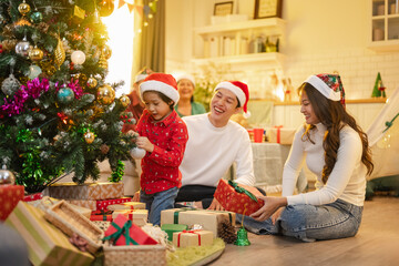 Obraz premium family, christmas, happy family, families, celebration, festive, festivity, asian family, Happy Asian family decorating Christmas tree and exchanging gifts together at home.
