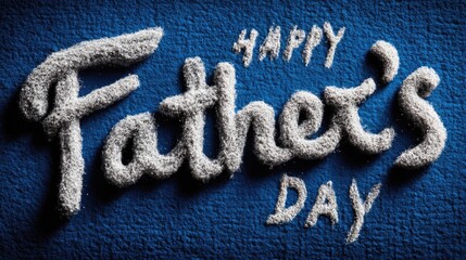 The words "Happy Father's Day" are written in textured, light-colored sand on a textured blue surface.