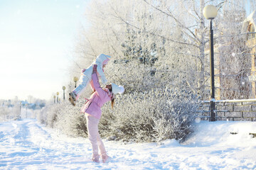 Winter walk on the street on a sunny frosty day. Family with children play snowballs in the park. Winter holidays and family vacation.
