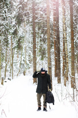 Naklejka premium Outdoor portrait of handsome man in coat and scurf. Bearded man in the winter woods.