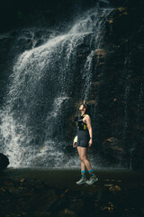 Obraz premium Nature Enthusiast Standing in Front of Majestic Waterfall with Splashing Water in Lush Forest Setting, Capturing Adventure and Serenity in the Outdoors