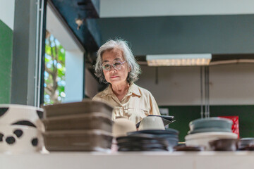 Senior Female Business Owner Inspecting Ceramics
