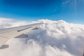 View from the airplane window at a beautiful cloudy sky and the airplane wing