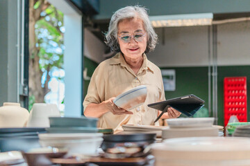 Senior Female Business Owner Inspecting Ceramics