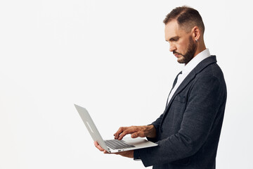 A professional man in business attire uses a laptop against an isolated white background, conveying focus, determination, and confident emotion during work tasks.