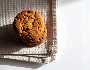 A stack of delicious cookies on a textured beige cloth, bathed in sunlight
