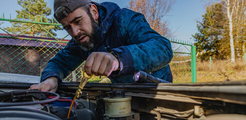 Man performs car maintenance in nature on a clear day