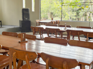 Empty Wooden Tables and Chairs in a Restaurant with Green Outdoor View