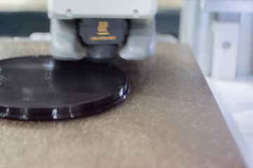 3D printer close up. Working 3D printer in process of printing object from molten black plastic. 3D printer creating model by flowing liquid plastic from extruder of printer. 3D printing technology